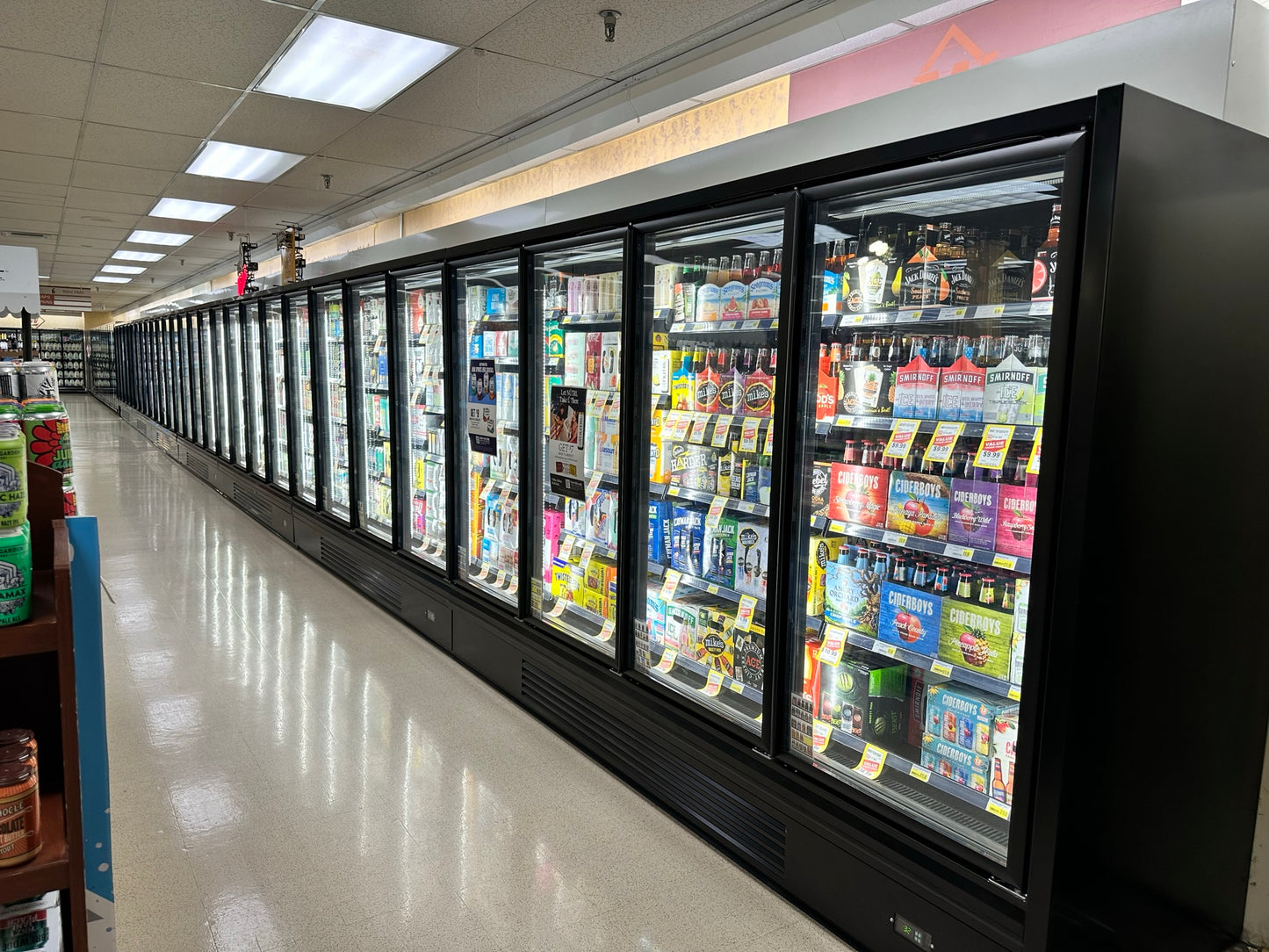 grocery store refrigeration lineup of black glass Door Coolers filled with beer and various alcoholic beverages